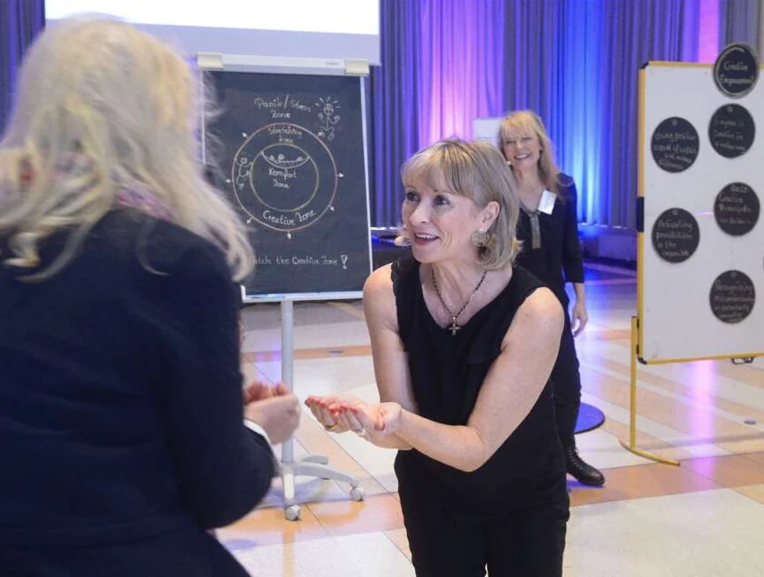 Marguerite leading a participant through a hands-on exercise beside a flipchart of creative zones.