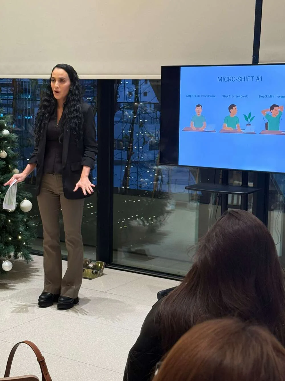 A facilitator presenting to an office group beside a screen