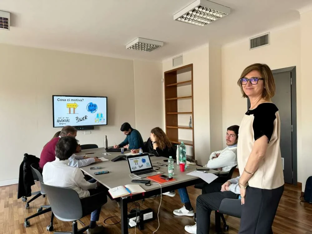 A facilitator standing at the head of a meeting table while managers work through a session on decisions