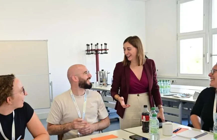 A facilitator laughing with participants around a workshop table