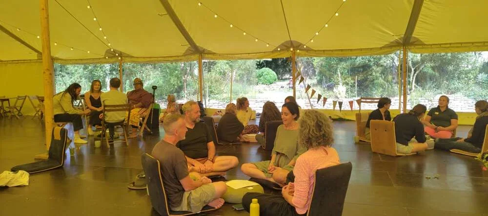 Colleagues seated in pairs inside a tent, talking and listening to one another