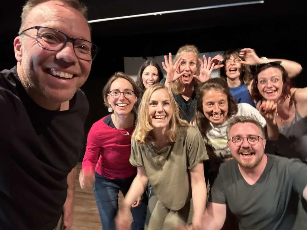 A facilitator and participants laughing together in a group photo