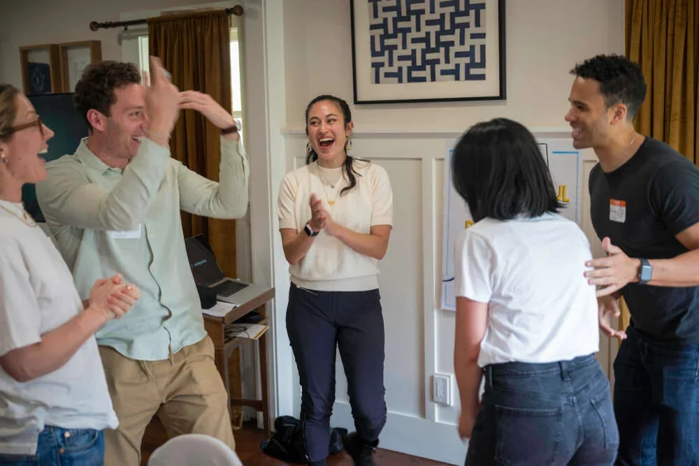 Colleagues laughing and talking during a team workshop in a living-room setting
