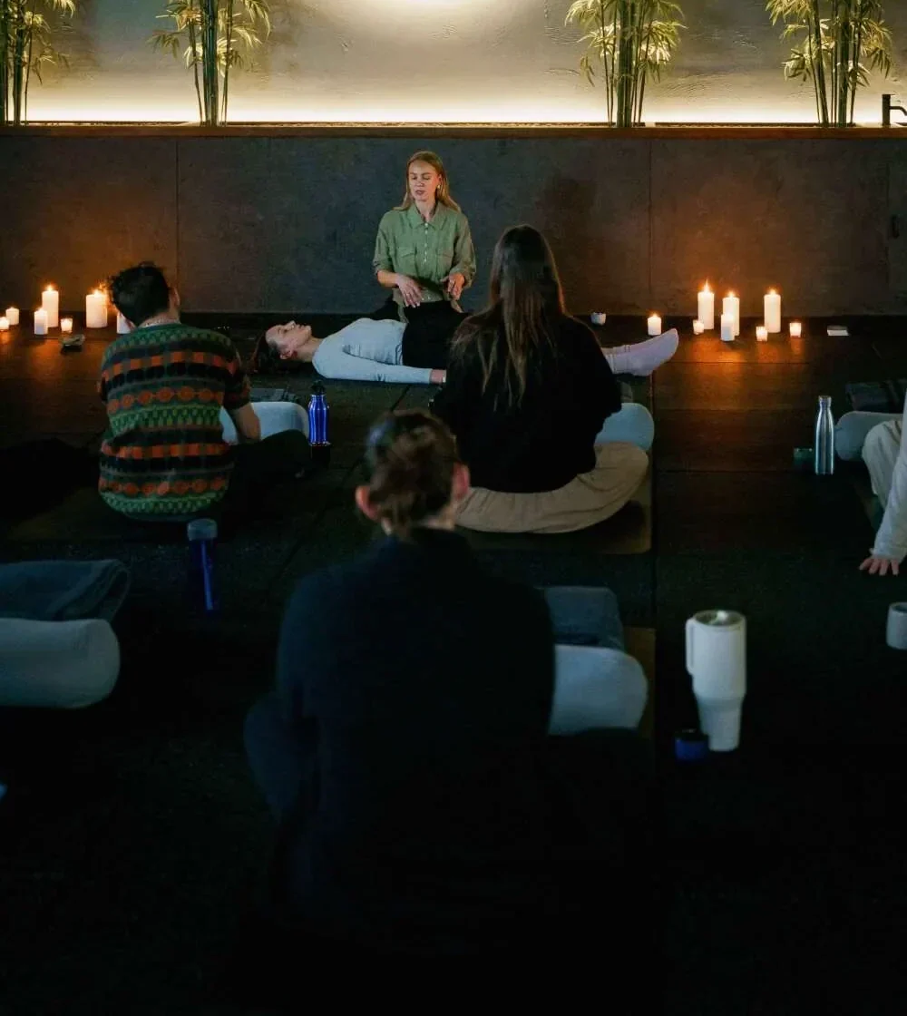 Tania guiding a candlelit breathwork session for a group seated on mats