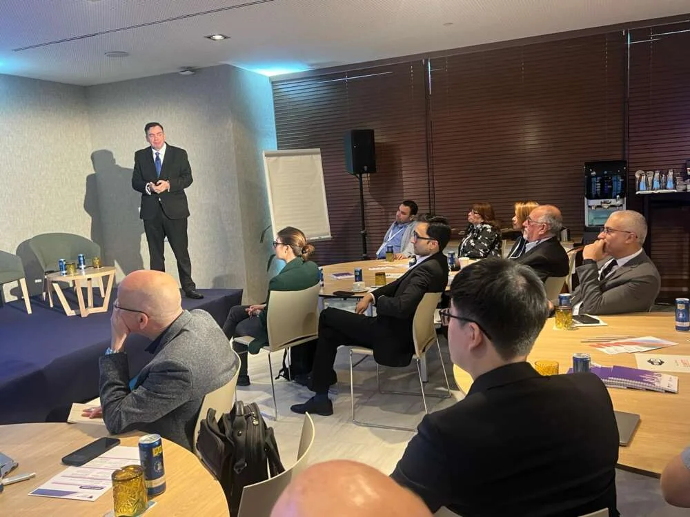 Brian speaking to attendees seated at round tables in a seminar room