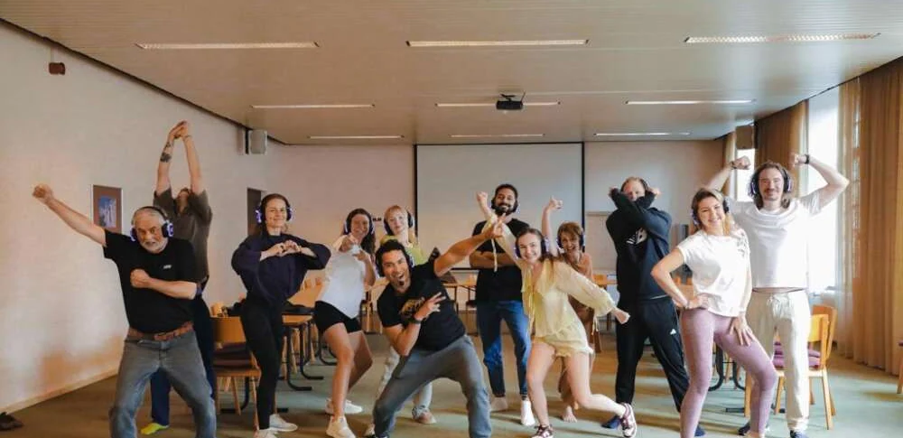 Colleagues in headphones striking a pose together in a meeting room during an energiser