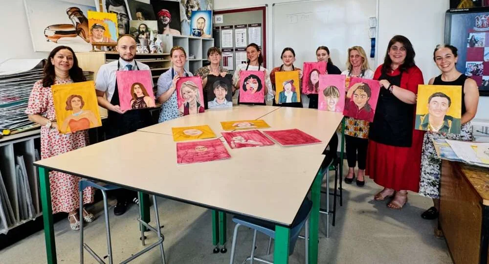 Guests smiling as they hold up the bright portraits they painted