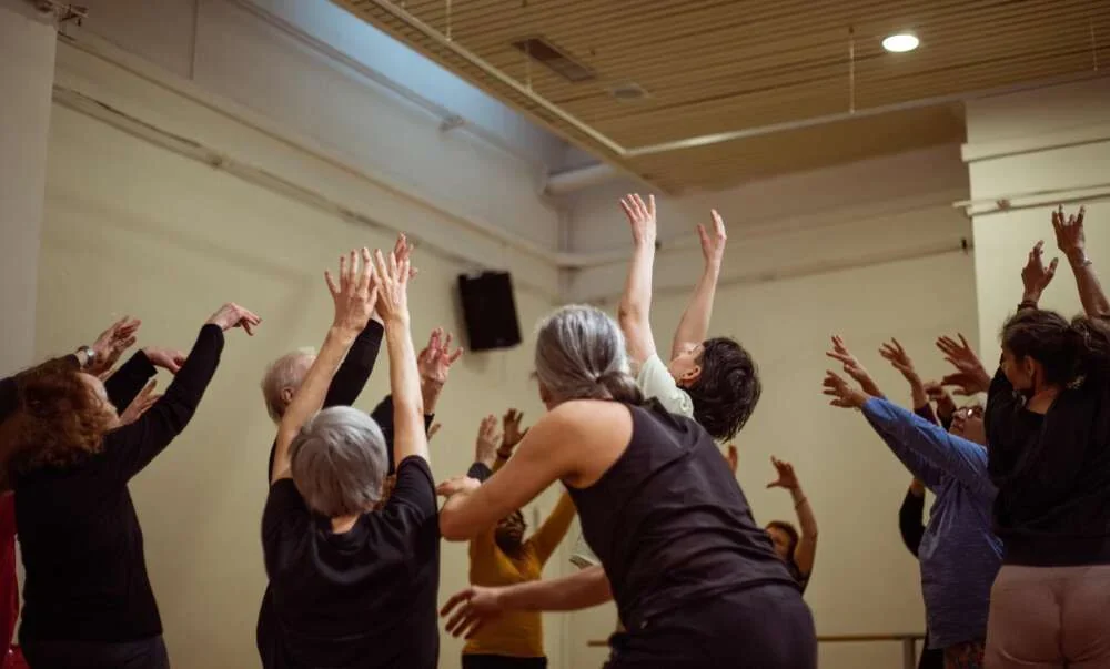A group raising their arms to the ceiling during a joyful dance session
