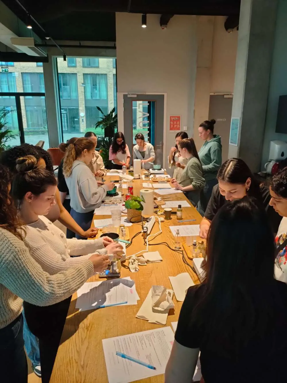 Colleagues blending their own natural skincare along a long workshop table