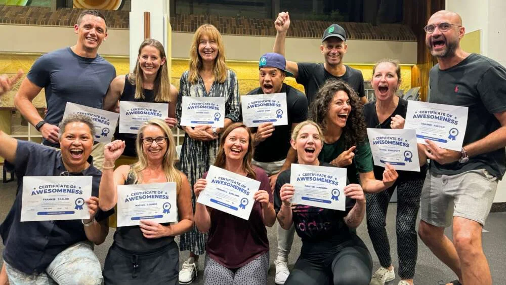 A team holding up their certificates after an improv workshop