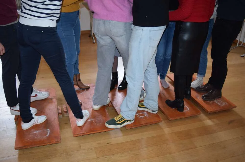 A team balancing together on small tiles during a bridge-building challenge