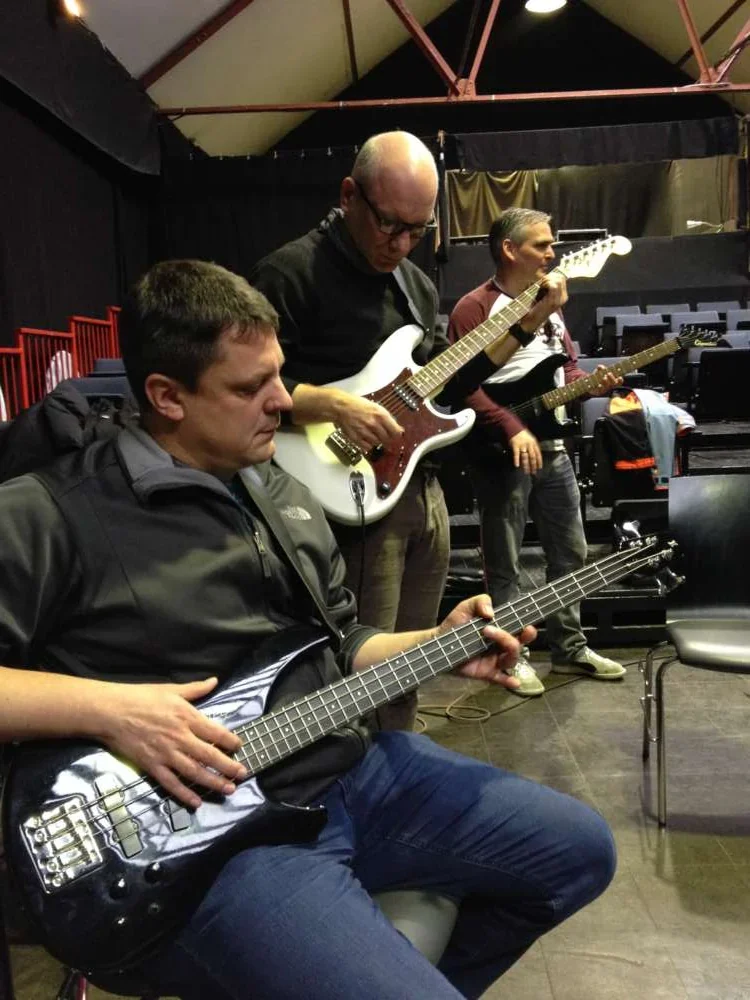 Colleagues playing bass and electric guitar together during a band session