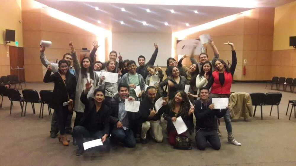 A group cheering with arms raised at the end of an improvisation workshop