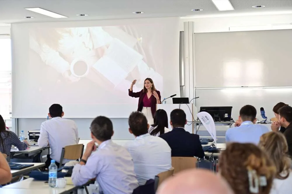 A trainer presents to leaders seated at tables in a bright seminar room