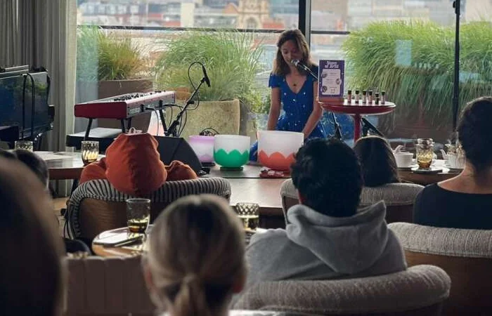 Jane singing beside crystal bowls for guests seated in a bright lounge