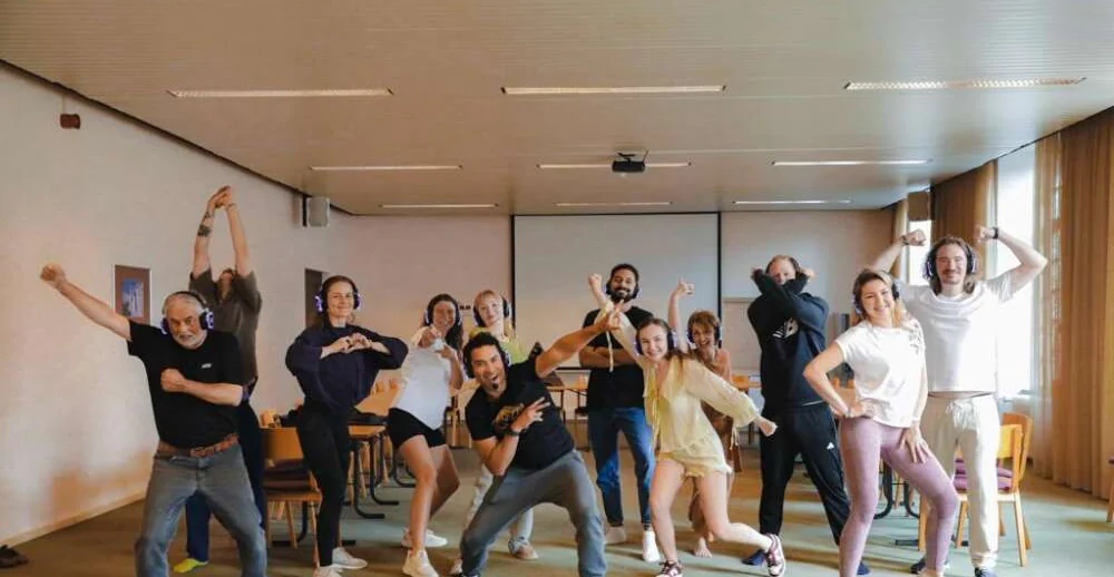 Colleagues in headphones striking playful poses together in a training room