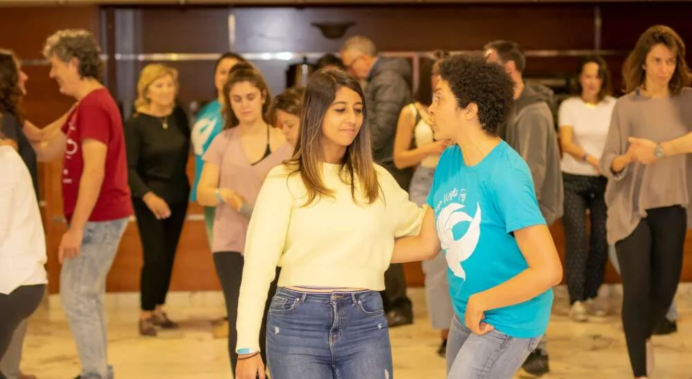 Deux collègues dansent ensemble au centre d’un groupe en atelier