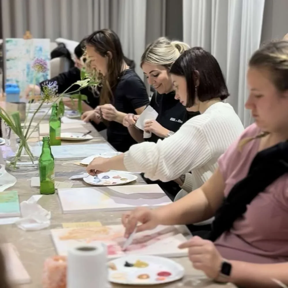 Des collègues peignent côte à côte autour d’une longue table pendant un atelier créatif