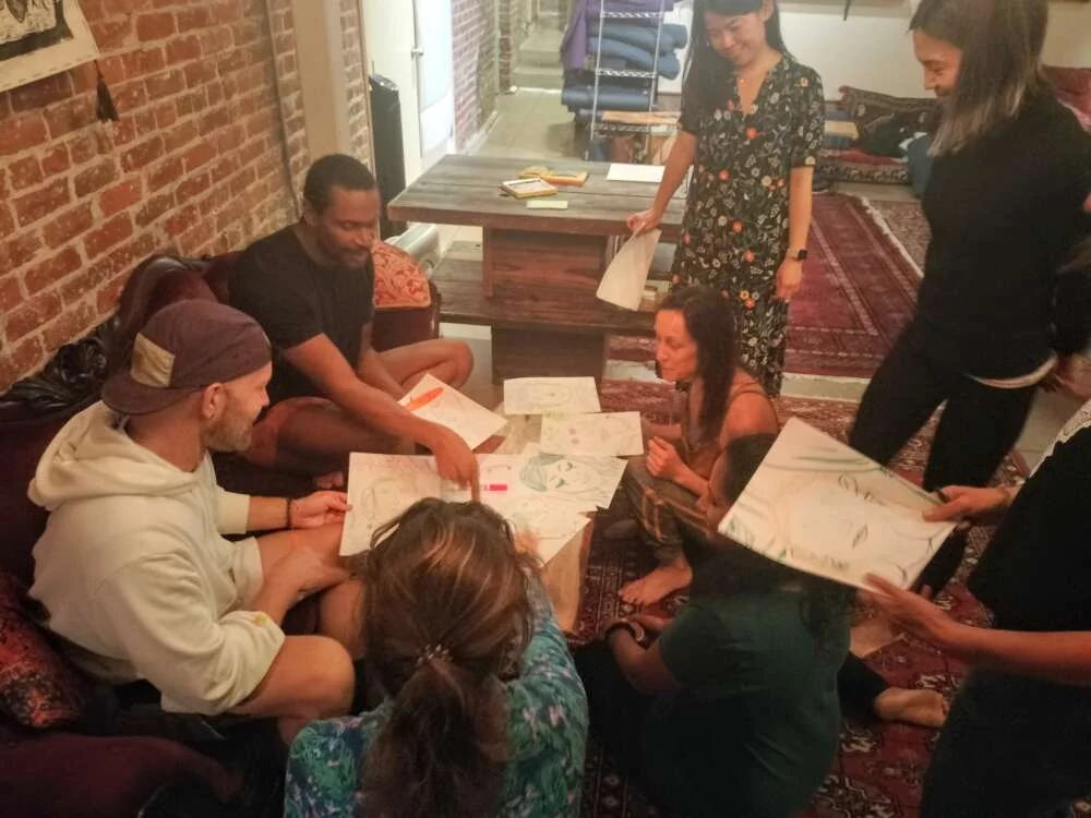 A team sharing sketches on rugs and a low table in a brick-walled loft