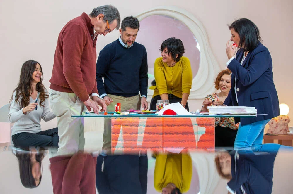 Leaders laughing around a glass table as they build an idea together