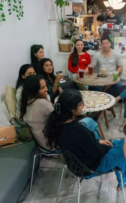 Colleagues smiling in a seated circle at a café during an applied improvisation session