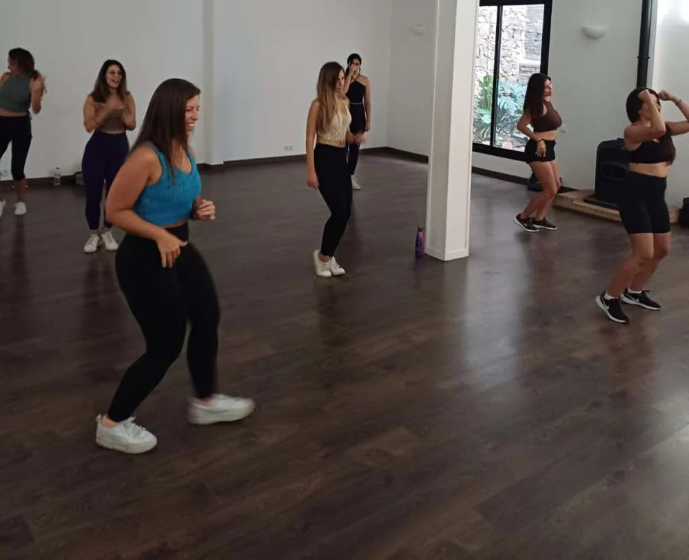 A group laughing through a dance class in a bright studio