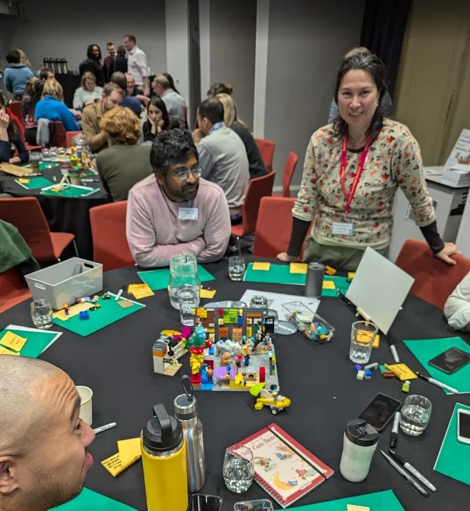 Colleagues at round tables building LEGO models during a facilitated strategy workshop
