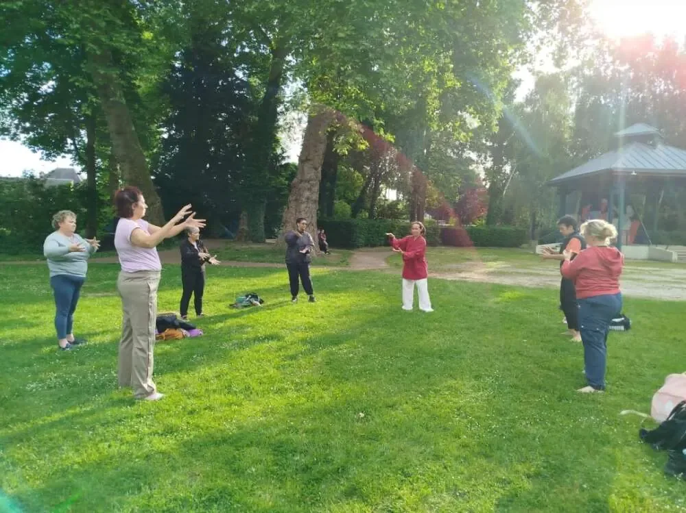 Martha leading a qi gong group in a sunlit park