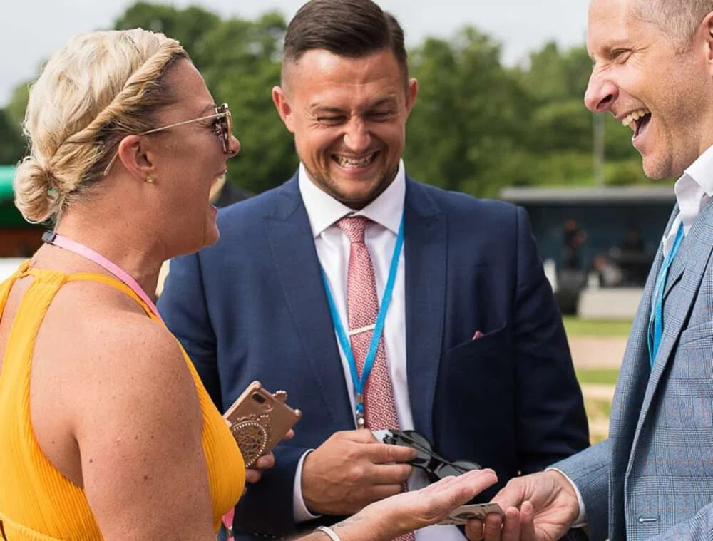 Guests laughing in disbelief as a magician performs a close-up trick at an outdoor corporate event