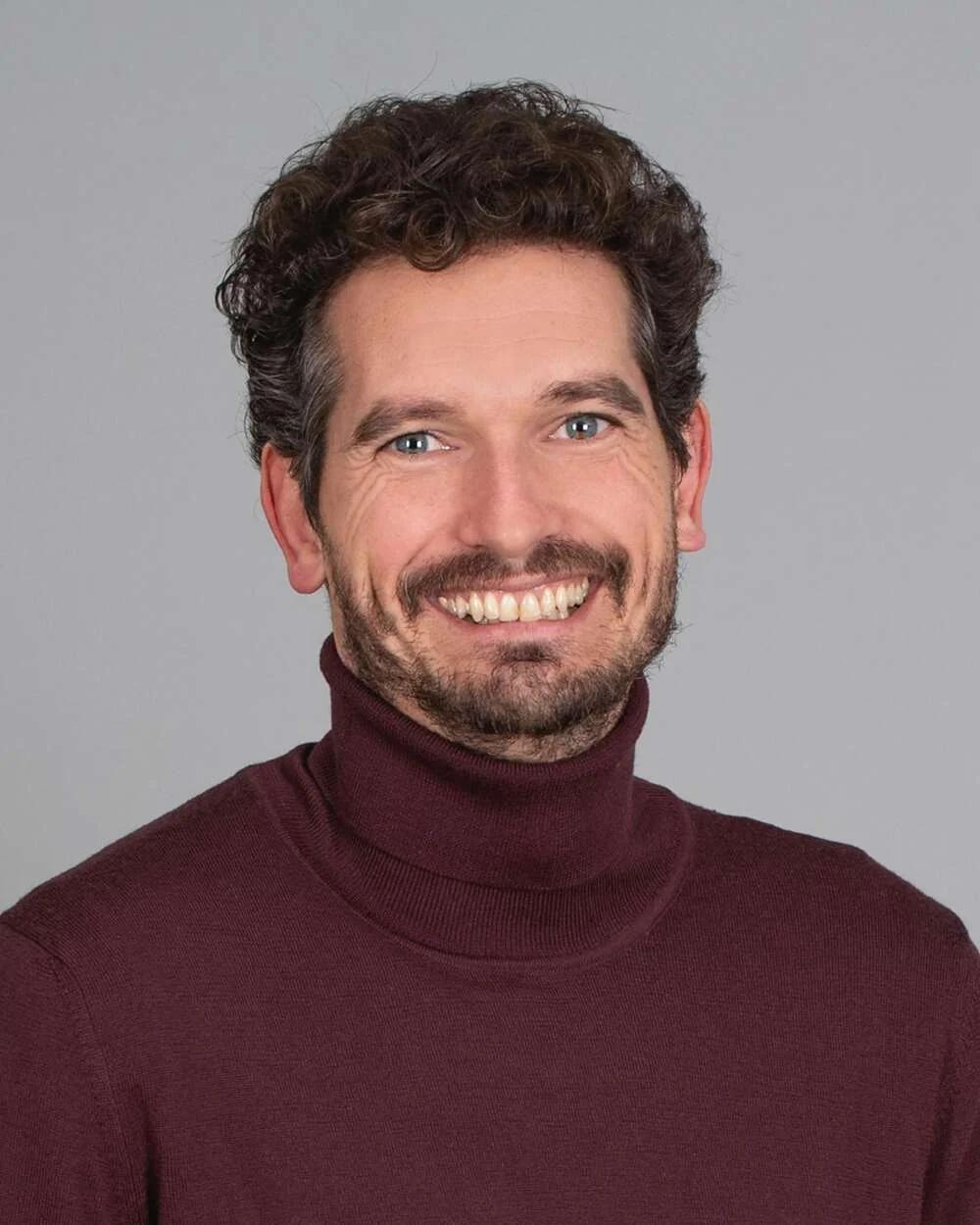 Portrait of Elias smiling in a dark red jumper