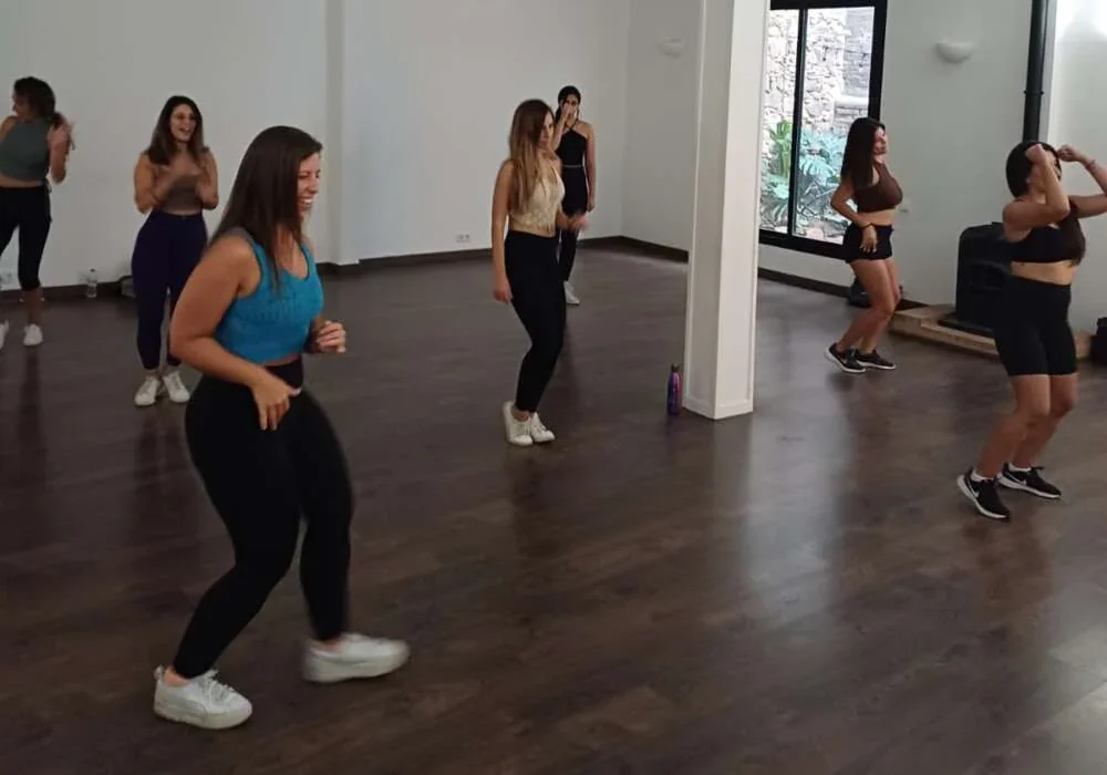 Colleagues dancing a choreography together in a bright studio with wooden floors