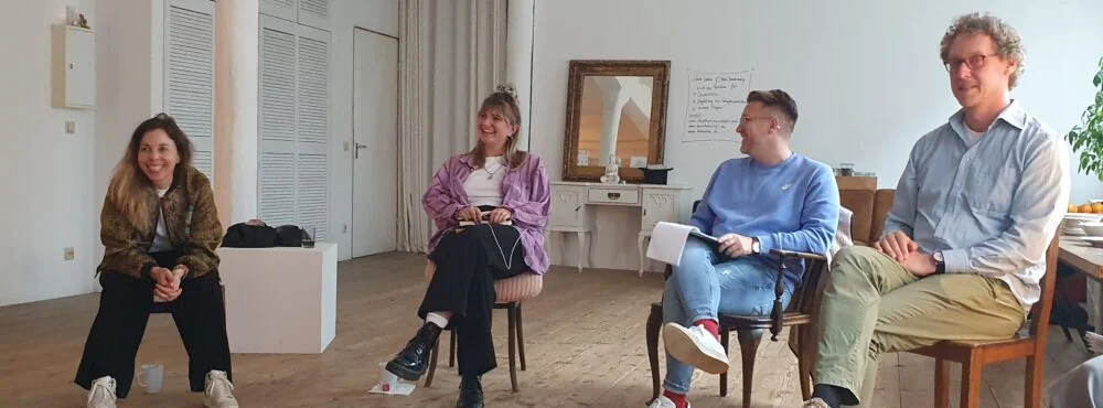 Four colleagues smiling in a facilitated circle in a bright loft